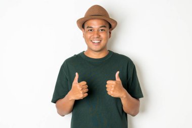 30 yaşlarında Asyalı erkekler şapka takıyor, koyu yeşil tişörtler giyiyor ve başparmaklarını gösteriyorlar..