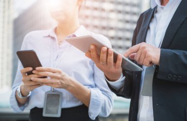 Tablet ve akıllı telefon kullanan işadamı ve kadın ellerini kapat.