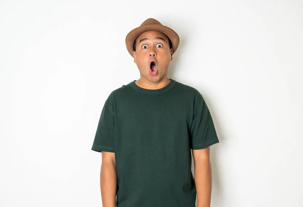 Young Asian man with hat feels shock and surprise with overly face expression.