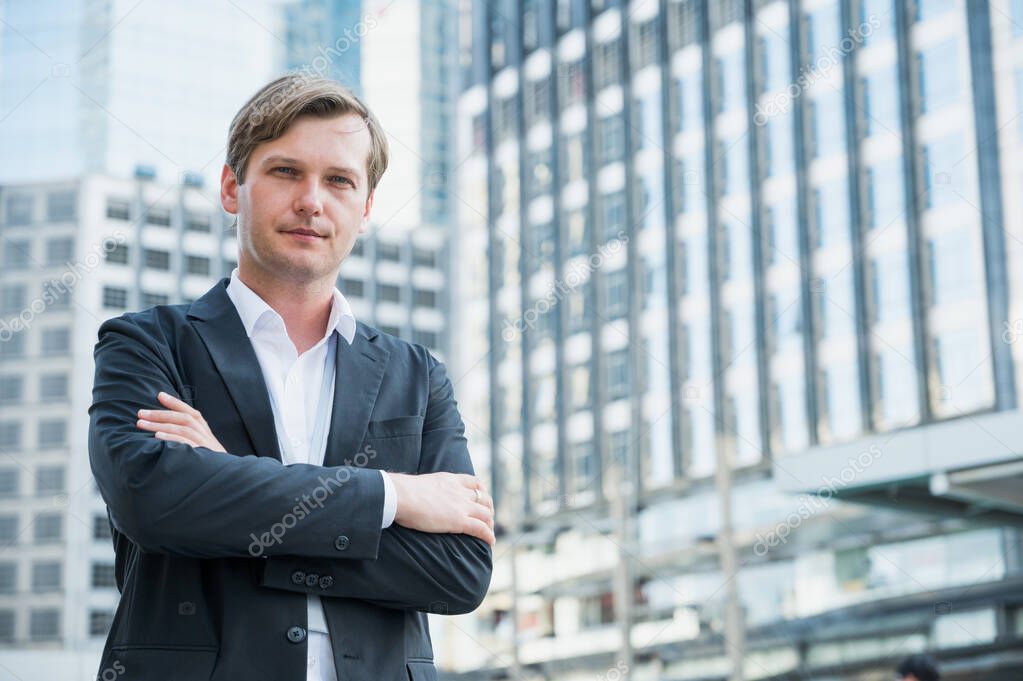 Businessman standing with arms crossed on business building background