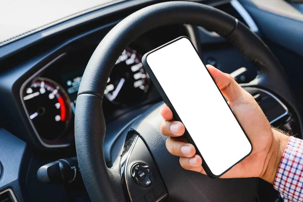 Hand holding blank screen of smartphone while driving car.