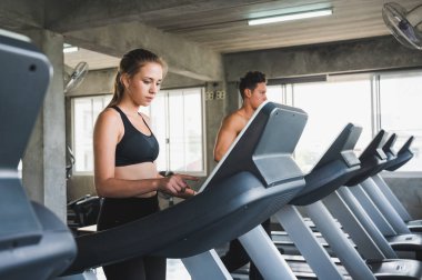 Genç çift her zaman sağlıklı kalmak için koşu bandında koşuyor.