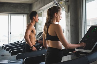 Genç çift her zaman sağlıklı kalmak için koşu bandında koşuyor.