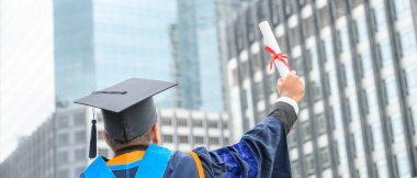 Mutlu mezun. Mezuniyet elbiseli mutlu Asain adam şehir geçmişi üzerine diplomasını elinde tutuyor..