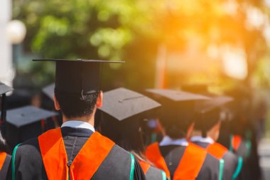 Mezunların arka görünüşü üniversitedeki mezuniyet törenine katılıyor. Üniversite teması konseptinde eğitim mezuniyeti.