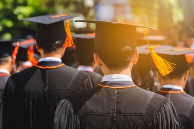 Mezunların arka görünüşü üniversitedeki mezuniyet törenine katılıyor. Üniversite teması konseptinde eğitim mezuniyeti.