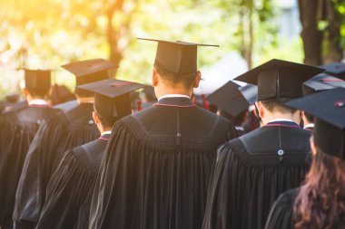 Mezunların arka görünüşü üniversitedeki mezuniyet törenine katılıyor. Üniversite teması konseptinde eğitim mezuniyeti.