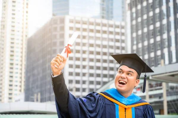 毕业快乐 穿着毕业礼服 手握城市背景文凭的快乐艾塞曼 — 图库照片