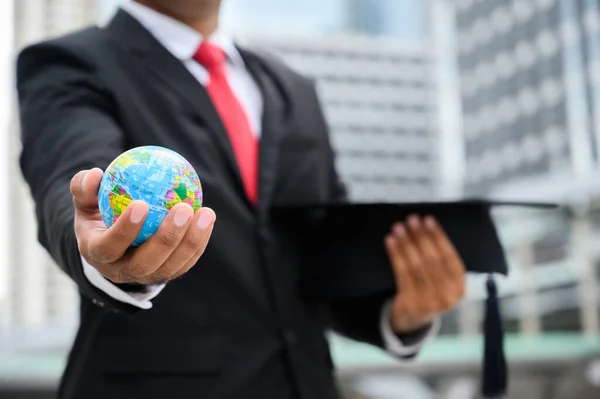 Close up Businessman holding Global Earth and Graduation cap in hand for education concept.