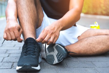 Bağcıklarını bağlayan koşucu genç adam koşu pistinde yarışa hazırlanıyor..