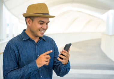 Genç Asyalı adam akıllı telefon kullanıyor..