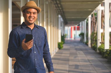 Genç Asyalı adam akıllı telefon kullanıyor..