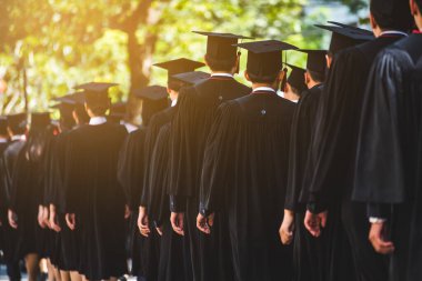 Mezunların arka görünüşü üniversitedeki mezuniyet törenine katılıyor. Üniversite teması konseptinde eğitim mezuniyeti.