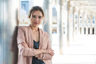 Ofis geçmişinde kollarını kavuşturmuş gülümseyen genç bir iş kadını portresi..