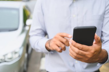 Aracın yanında duran akıllı telefonu kullanan bir iş adamı. Yol konseptinde yardım için akıllı telefon kullanan bir adam bozulmuş bir araba kullanıyor..