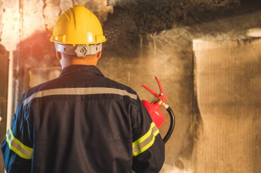 Genç Asyalı itfaiyeci, itfaiyeciler binada yanan yangın söndürücüleri kullanıyorlar..