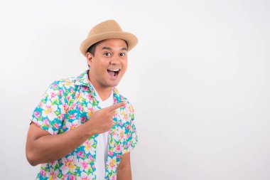 Şok olmuş genç adam boş bir yeri işaret ediyor. Yazlık gömlek giyiyor..