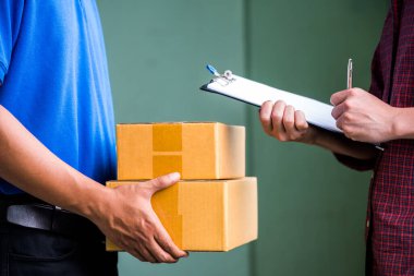 Paketini teslimatçıdan almak için erkek eli imzalıyor..