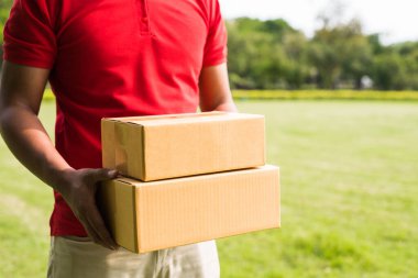 Paket karton kutulu kırmızı üniformalı teslimatçı.