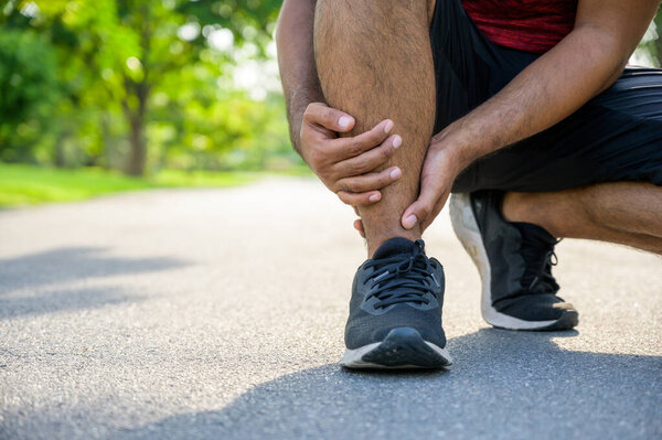 Broken twisted ankle. Runner touching foot in pain due to sprained ankle