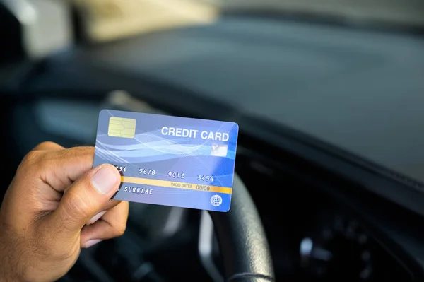 Hand man holding a credit card inside car. This picture is about shopping. Spending money Expenses related to car bills by credit card