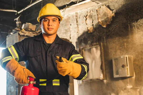 Genç Asyalı itfaiyeci, itfaiyeciler binada yanan yangın söndürücüleri kullanıyorlar..