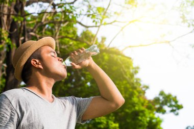 Halk parkında su içen Asyalı genç bir adam.