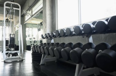 Salonun arka planındaki dambıllar pankart sunumu için. İyi sağlık için egzersiz temaları.