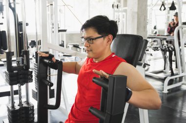 Güçlü kaslı Asyalı adam spor salonunda bisepslerde egzersiz yapıyor. Ağırlık antrenmanı konsepti.