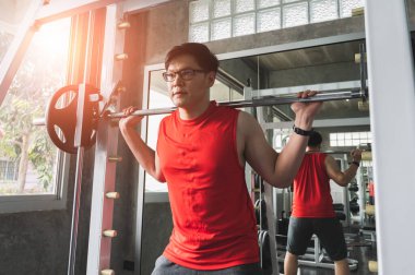 Güçlü kaslı Asyalı adam spor salonunda bisepslerde egzersiz yapıyor. Ağırlık antrenmanı konsepti.