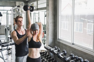 Çekici bir kadın spor salonunda kişisel antrenörle egzersiz yapıyor..