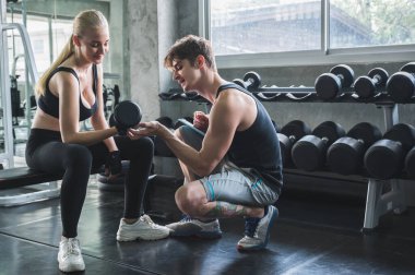 Çekici bir kadın spor salonunda kişisel antrenörle egzersiz yapıyor..