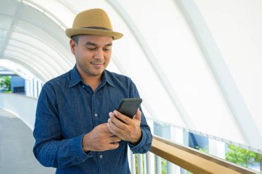 Genç Asyalı adam akıllı telefon kullanıyor..