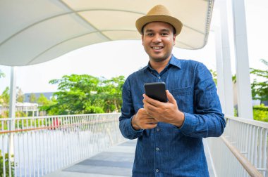 Genç Asyalı adam akıllı telefon kullanıyor..