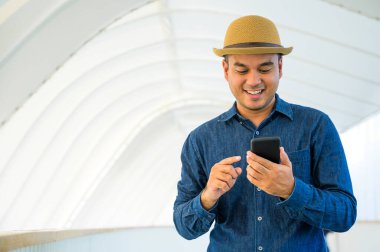 Genç Asyalı adam akıllı telefon kullanıyor..