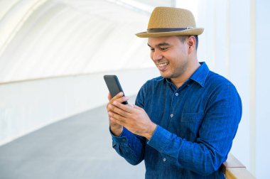 Genç Asyalı adam akıllı telefon kullanıyor..