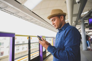 Gökyüzü treninde akıllı telefon kullanan Asyalı bir adam.