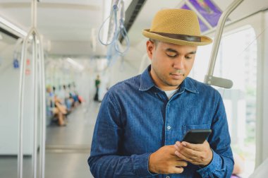 Gökyüzü treninde akıllı telefon kullanan Asyalı bir adam.