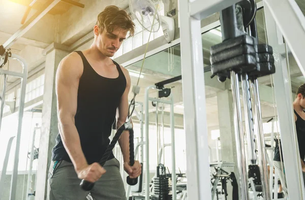 Beden eğitiminde güçlü kaslı adam pazularda egzersiz yapıyor. Ağırlık antrenmanı konsepti.