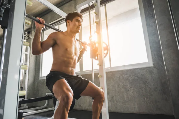 Beden eğitiminde güçlü kaslı adam pazularda egzersiz yapıyor. Ağırlık antrenmanı konsepti.