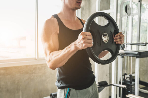 Strong muscular man workout in gym doing exercises at biceps.  Weight training concept.