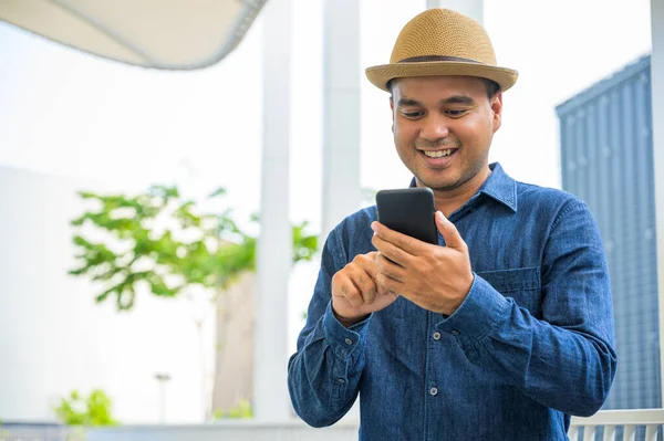 Genç Asyalı adam akıllı telefon kullanıyor..