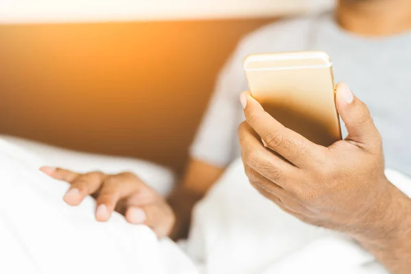 Man using smartphone on the bed.