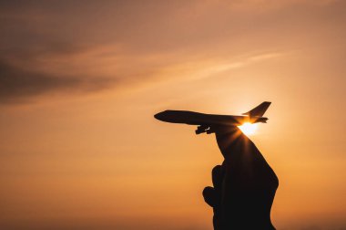 Oyuncak uçak tutan bir el Gün batımı ışığıyla gökyüzüne git