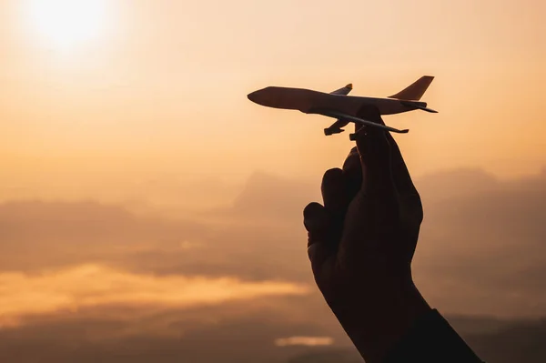 A hand holding a toy plane Go to the sky with sunset light