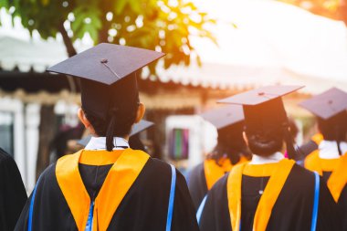 Mezunların arka görünüşü üniversitedeki mezuniyet törenine katılıyor. Üniversite teması konseptinde eğitim mezuniyeti.