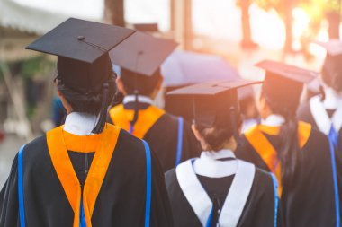 Mezunların arka görünüşü üniversitedeki mezuniyet törenine katılıyor. Üniversite teması konseptinde eğitim mezuniyeti.