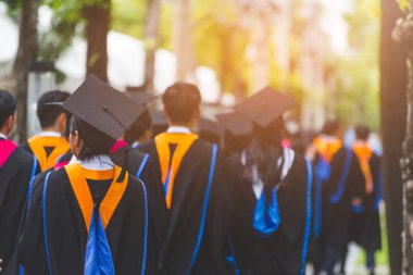 Mezunların arka görünüşü üniversitedeki mezuniyet törenine katılıyor. Üniversite teması konseptinde eğitim mezuniyeti.