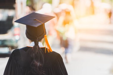 Mezunların arka görünüşü üniversitedeki mezuniyet törenine katılıyor. Üniversite teması konseptinde eğitim mezuniyeti.