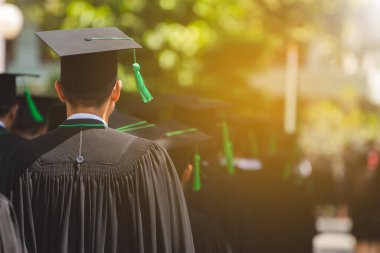 Mezunların arka görünüşü üniversitedeki mezuniyet törenine katılıyor. Üniversite teması konseptinde eğitim mezuniyeti.